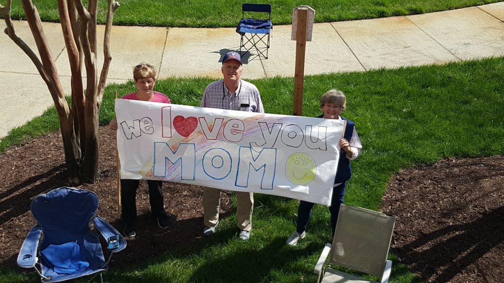 family showing a love sign to senior resident in Newport News, VA.