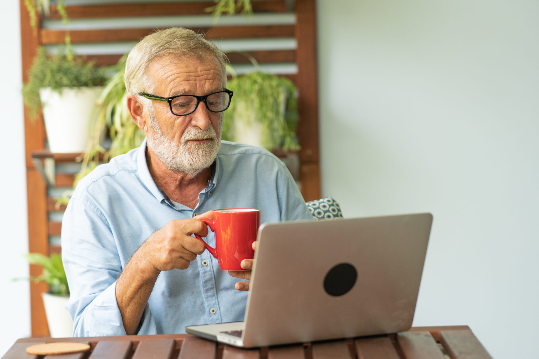 senior man drinking coffee on laptop