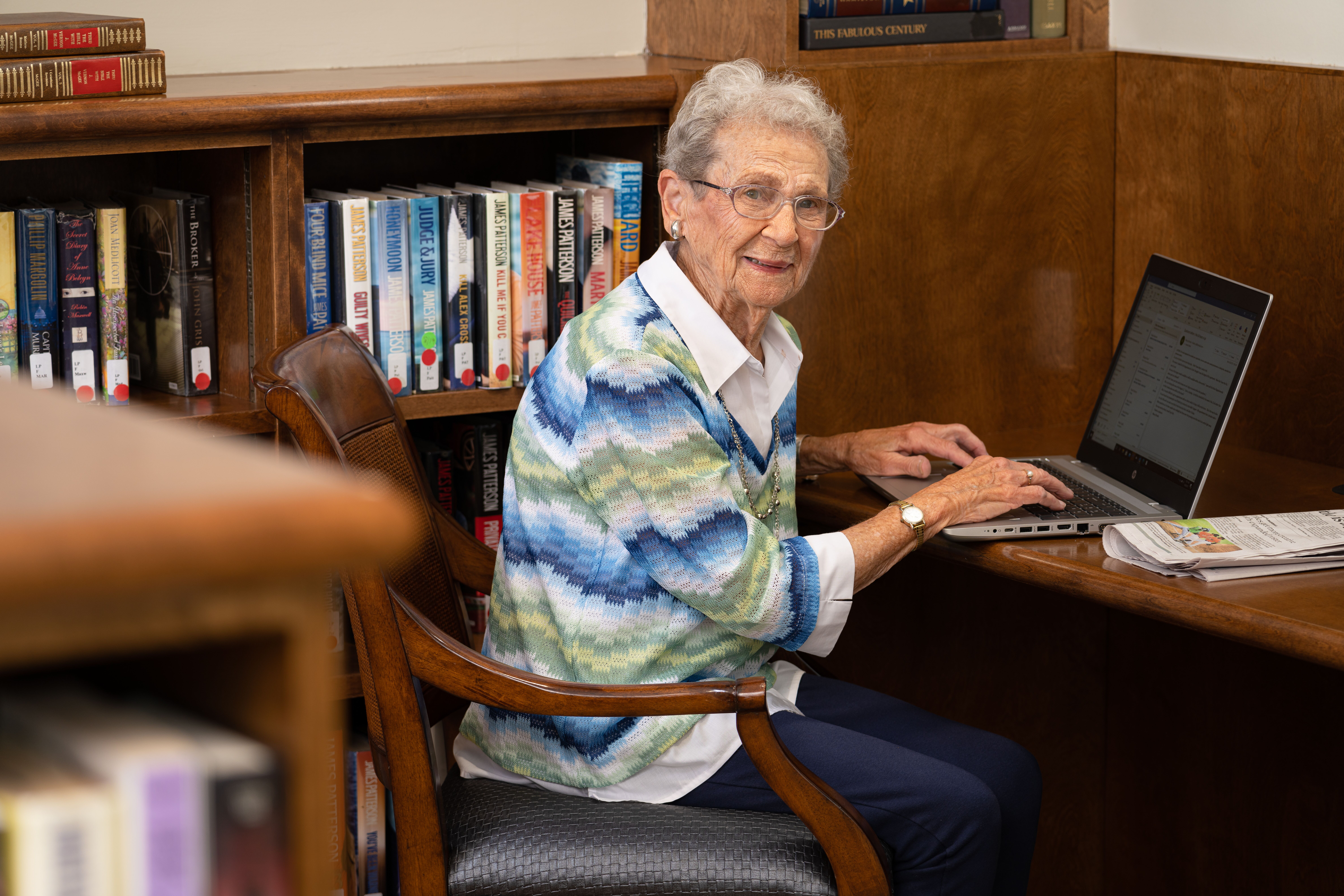 senior resident at The Chespeake on laptop in the library area