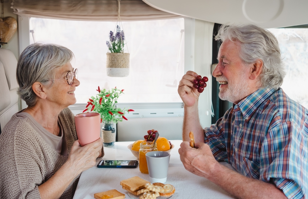 A senior man and woman enjoy breakfast at their RV's kitchenette.